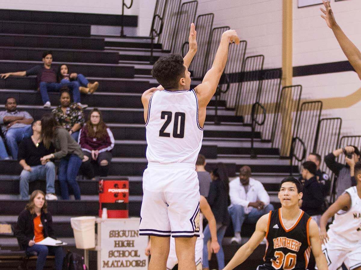 A student basketball player making a jump shot.