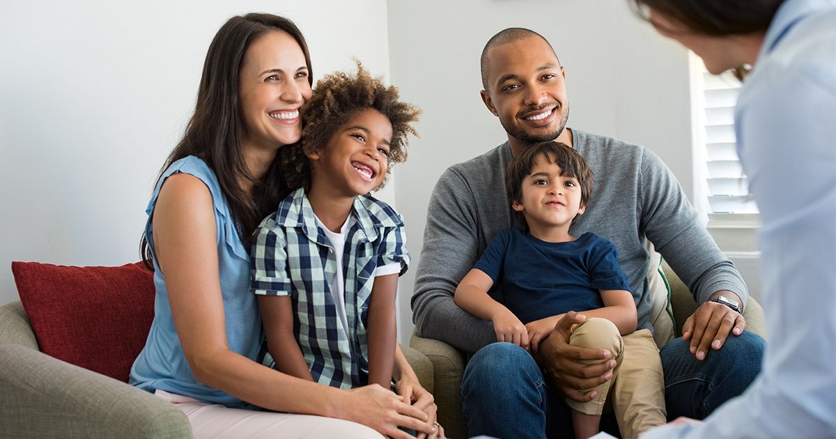 A family smiling while speaking to a counselor 