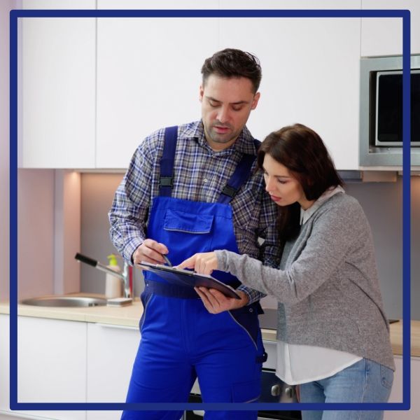 A Plumbing Plus plumber reviews an upfront service quote on a clipboard with a San Diego homeowner in her kitchen. A Plumbing Plus plumber reviews an upfront service quote on a clipboard with a San Diego homeowner in her kitchen.