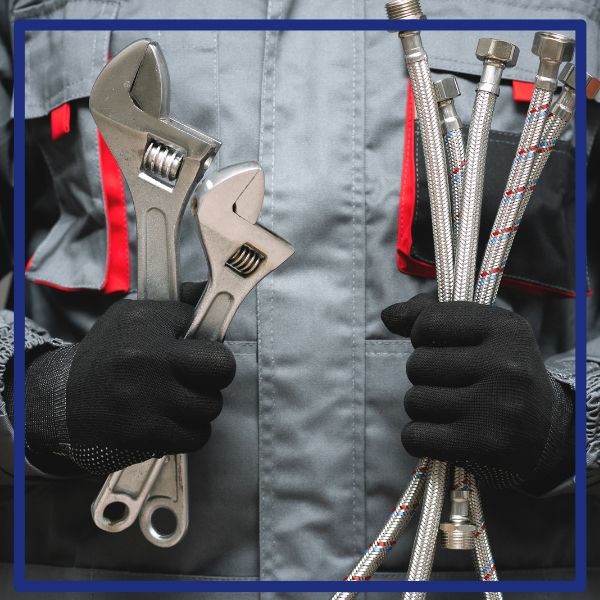 A well-equipped emergency plumber holding wrenches and braided steel supply lines, ready for any plumbing repair. A well-equipped emergency plumber holding wrenches and braided steel supply lines, ready for any plumbing repair.