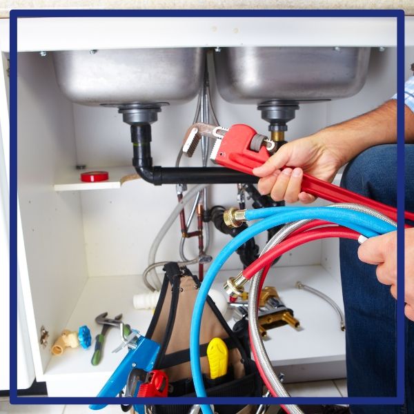 A Plumbing Plus plumber prepared with a wrench and new supply lines for a kitchen sink repair in Alpine.