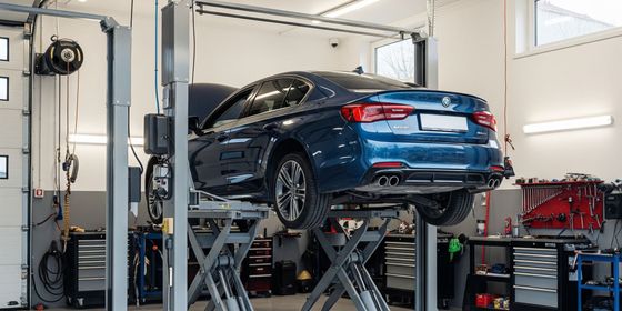 A pristine auto repair garage, showcasing a car elevated on a hydraulic lift, ready for service.