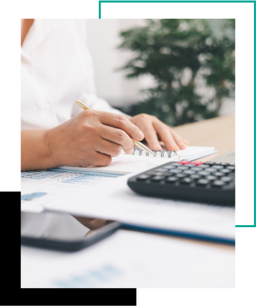 A business person using a calculator and a laptop with a financial report on an office desk.