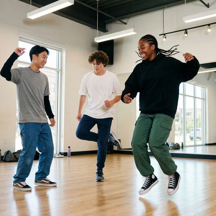 A diverse group of three teenagers energetically dances hip hop together in a brightly lit modern studio.