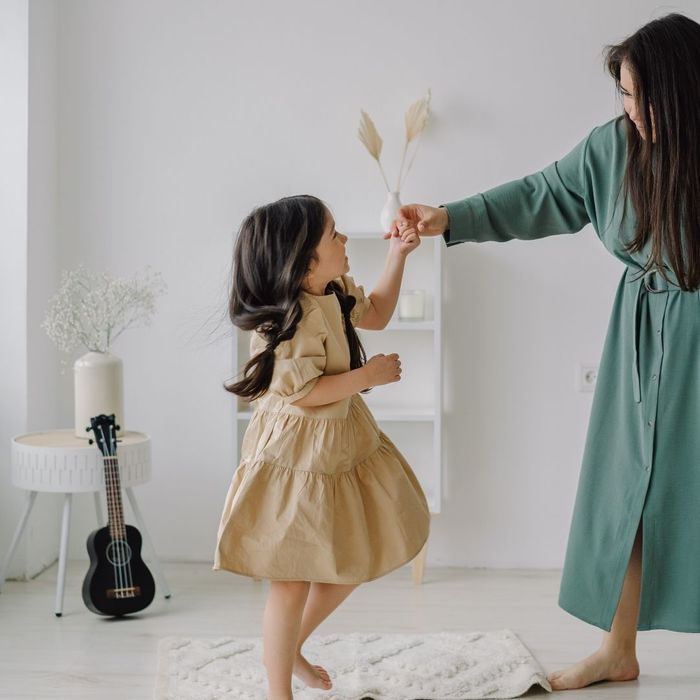 mother holding daughter's hand while she dances in room mother holding daughter's hand while she dances in room