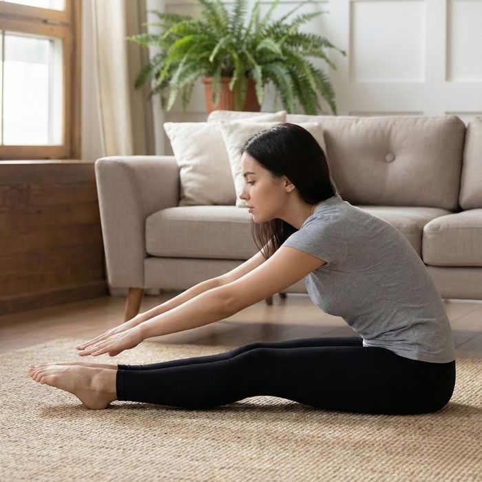 A gymnastics student performing a seated pike fold stretch to lengthen hamstrings and lower back safely.