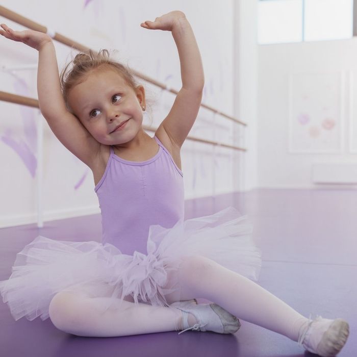smiling little girl in tutu and leotard in dance studio