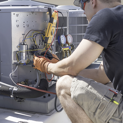 Man performing repairs on a broken air conditioner.