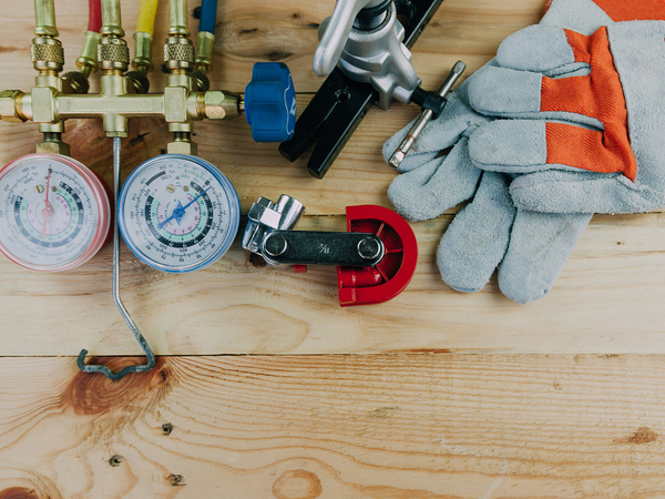 Air conditioning repair tools on a wooden workbench.