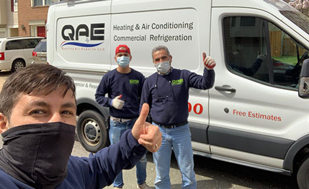 Image of QAE employees giving the thumbs up near a company vehicle