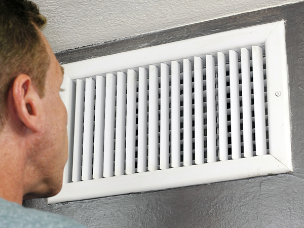Male examines an indoor air duct.