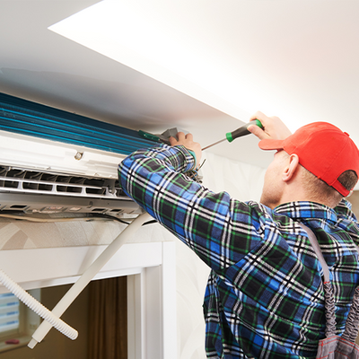 Man installing a new HVAC unit above a window.