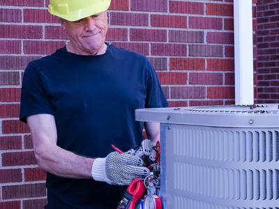  HVAC Technician diagnoses outdoor air conditioning condenser with tools and gauges.