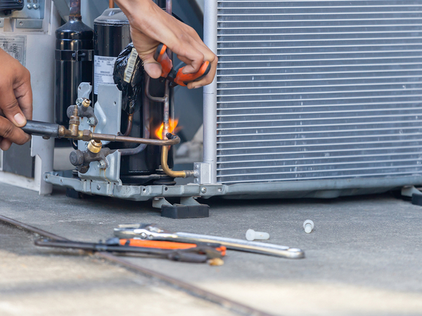 Air conditioning repair technician using a welder to fix a unit. Air conditioning repair technician using a welder to fix a unit.