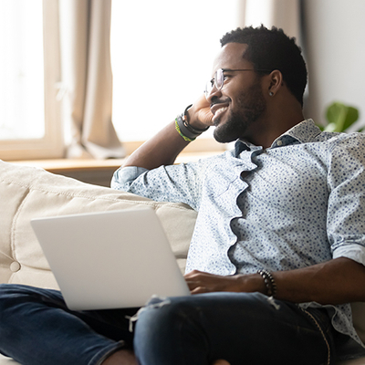 Man smiling while working on a computer and talking on the phone.