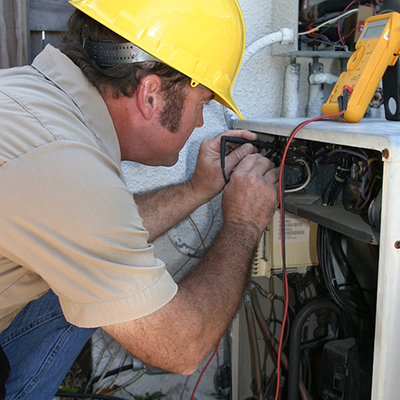 HVAC technician using tools to inspect a unit.