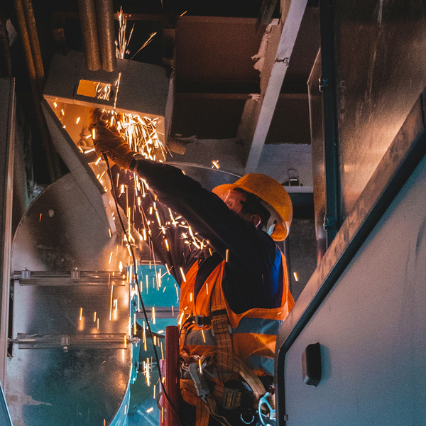 Male HVAC technician with angle grinder repairs the air duct in commercial building. Male HVAC technician with angle grinder repairs the air duct in commercial building.