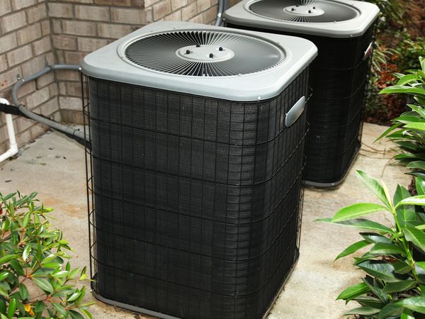 Central air conditioner units on cement slab outside.