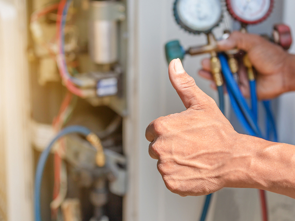 Air conditioning repair technician giving a thumbs up after fixing a unit. Air conditioning repair technician giving a thumbs up after fixing a unit.