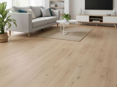 Bright living room with light wood-look laminate flooring, a comfortable grey sofa, white coffee table, and an entertainment console.