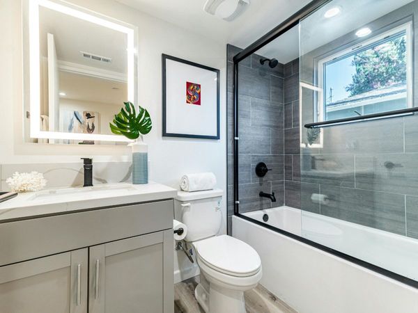 Modern bathroom remodel with custom tile work in the shower with glass door, mirror with lighting fixture