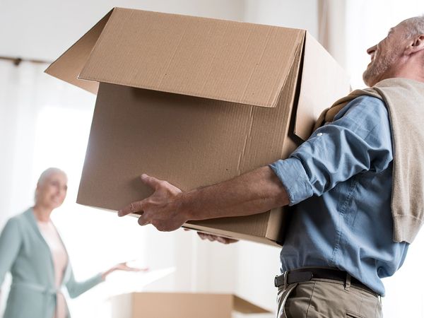 A older man moving a box while his wife watches