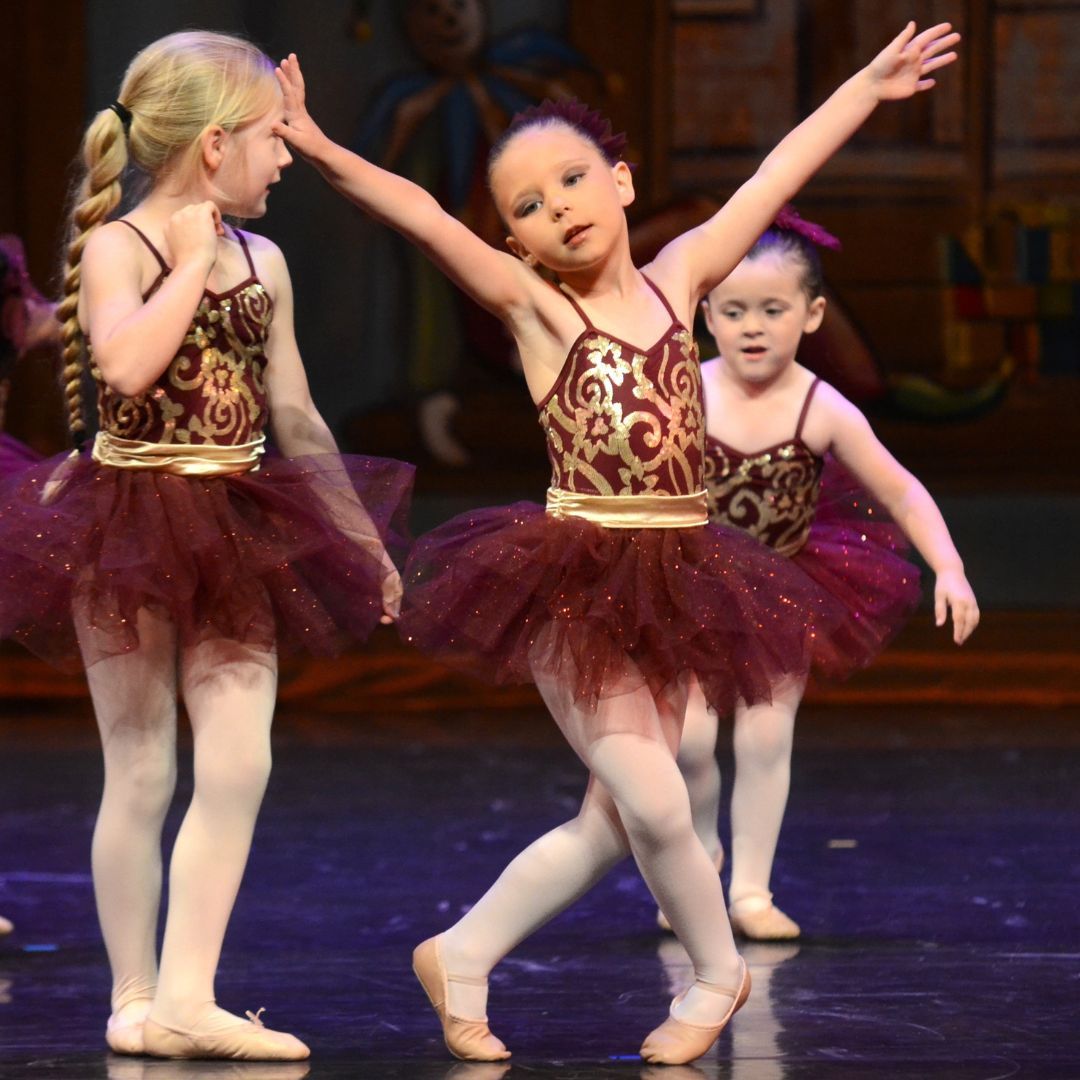 Three young girls performing at a dance recital. 