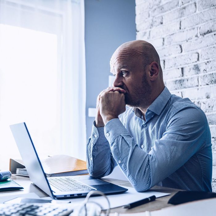 Person with a stressed expression using a laptop