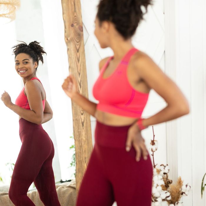 Woman in workout clothes smiling in mirror