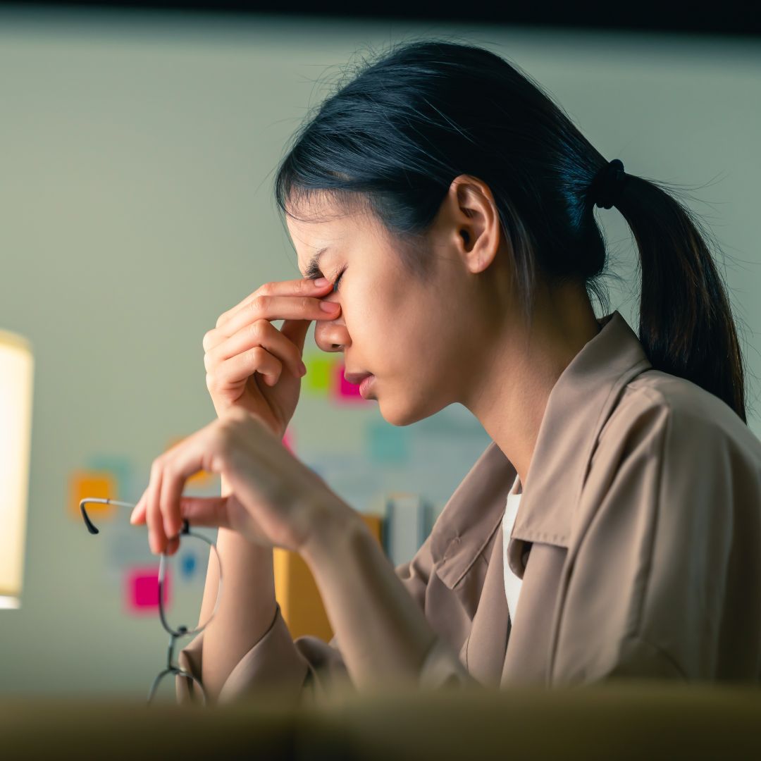 Tired person holding their forehead with an uncomfortable expression