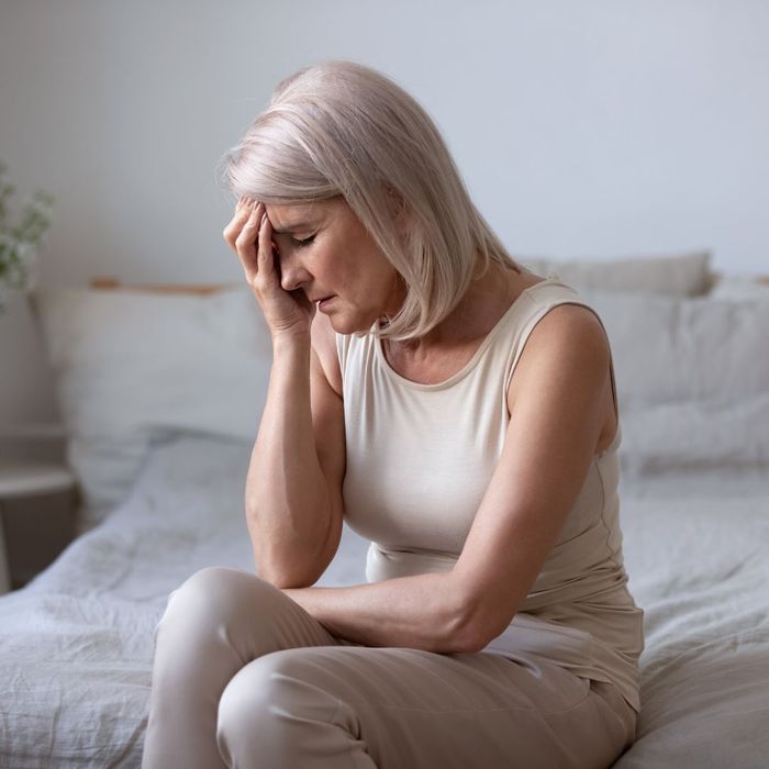 Mature person with an exhausted expression sitting on a bed