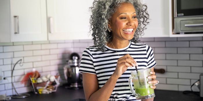 Person holding a green smoothing and smiling