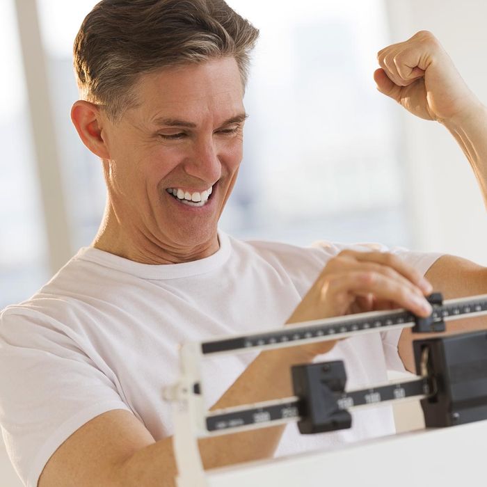 happy man weighing himself on a scale