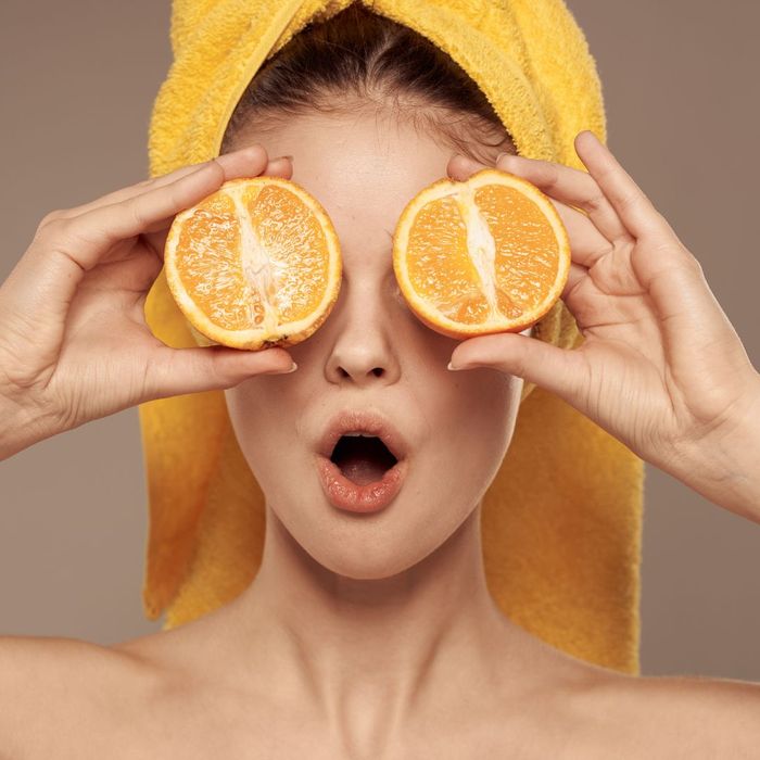 A women holding fresh oranges over her eyes