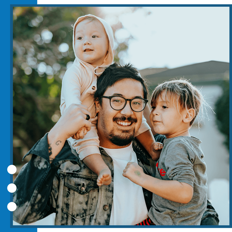 father wearing glasses holding two kids