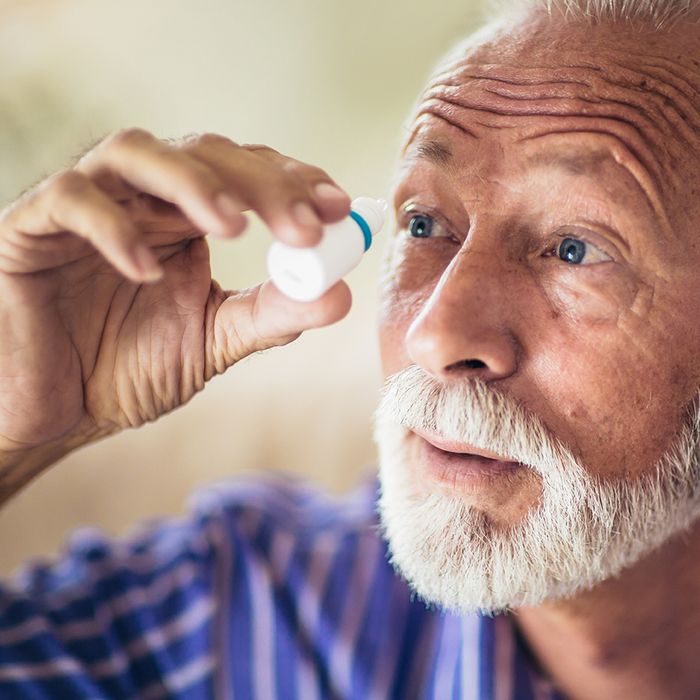 man using eye drops