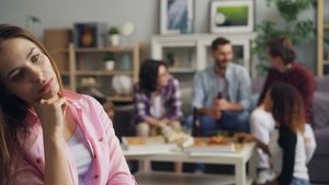 zoned out woman with friends talking in the background