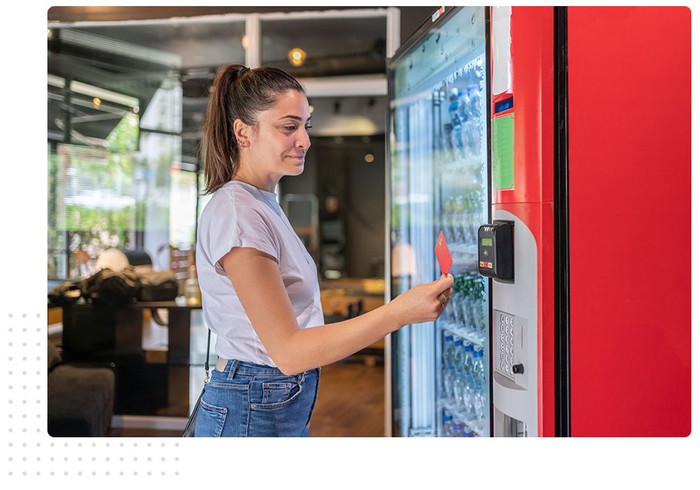 woman tapping credit card to vending machine