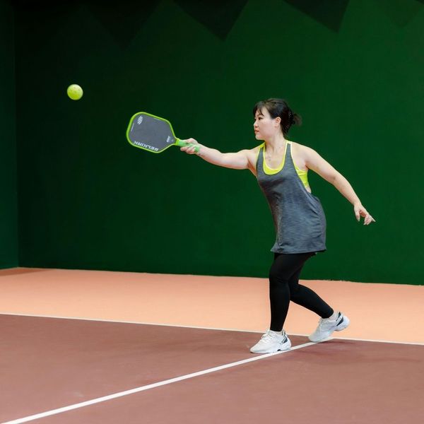 Woman playing pickleball on indoor court
