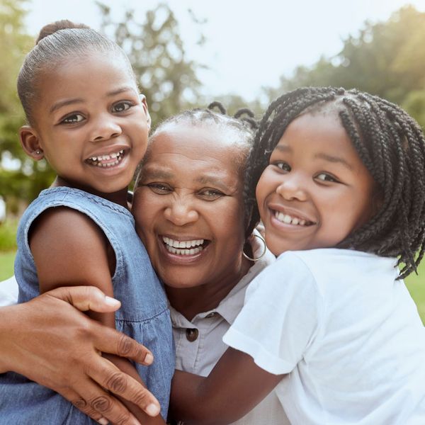 grandmother holding two grandaughters and smiling