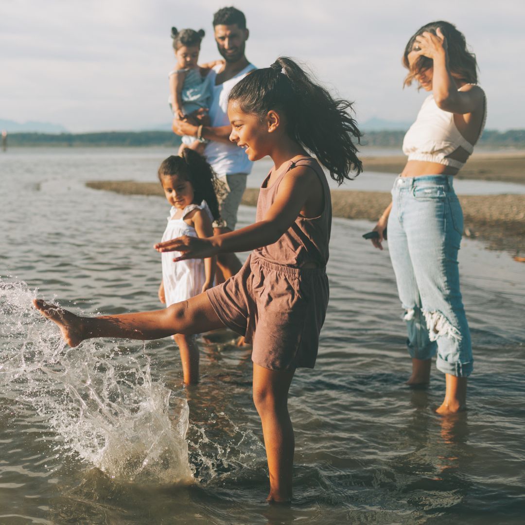 happy family putting feet in the water at the beach