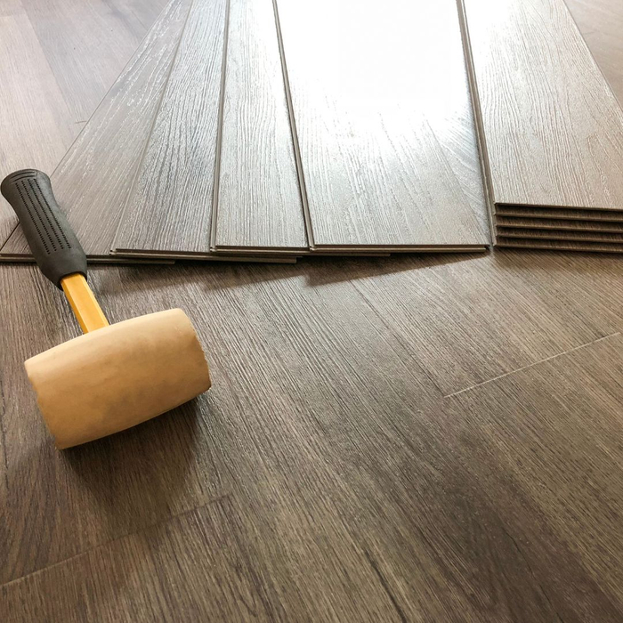 Planks of luxury vinyl with a rubber mallet next to it. 