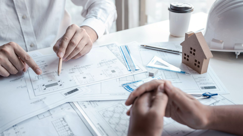 two men look over floor plan blueprints