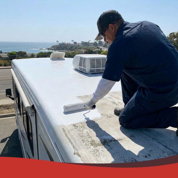 Professional technician applying white liquid armor roof coating to seal leaks and reflect UV rays.