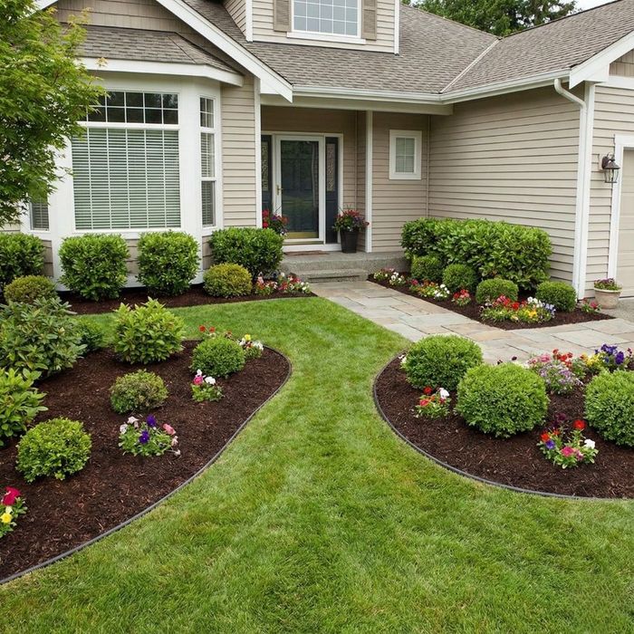 A beautiful home with a manicured front garden featuring neatly edged beds with fresh, dark brown mulch and colorful flowers in Shippensberg