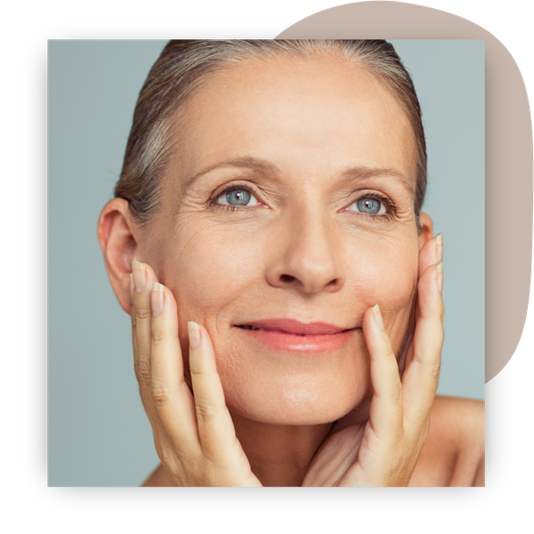 older woman smiling in mirror, hands on cheeks