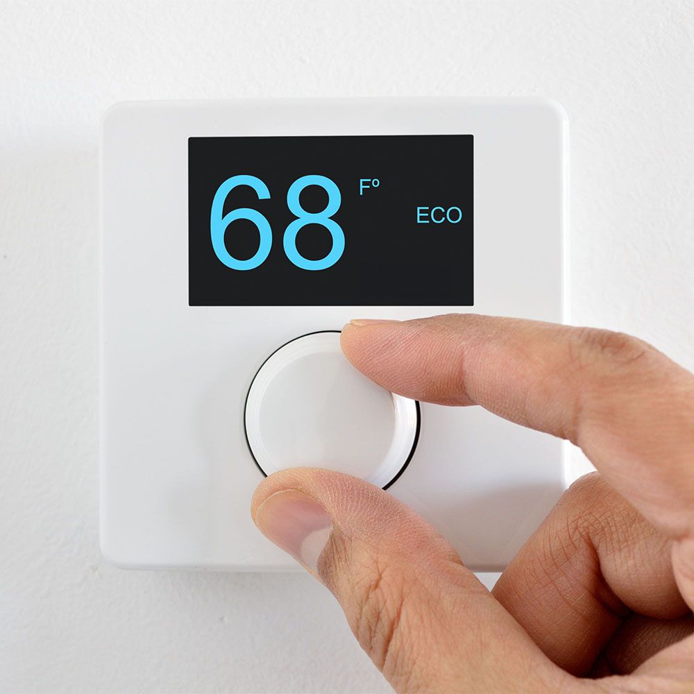 hand adjusting thermostat to 68 degrees