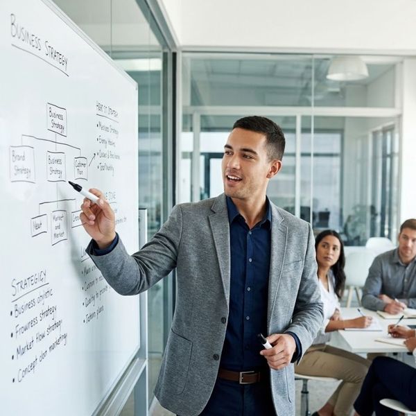 A professional presenting ideas confidently on a whiteboard.