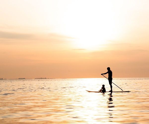 serene image of a father and child on a paddle board in the ocean