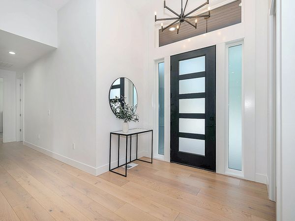 A modern entryway with a black front door with 5 glass panels